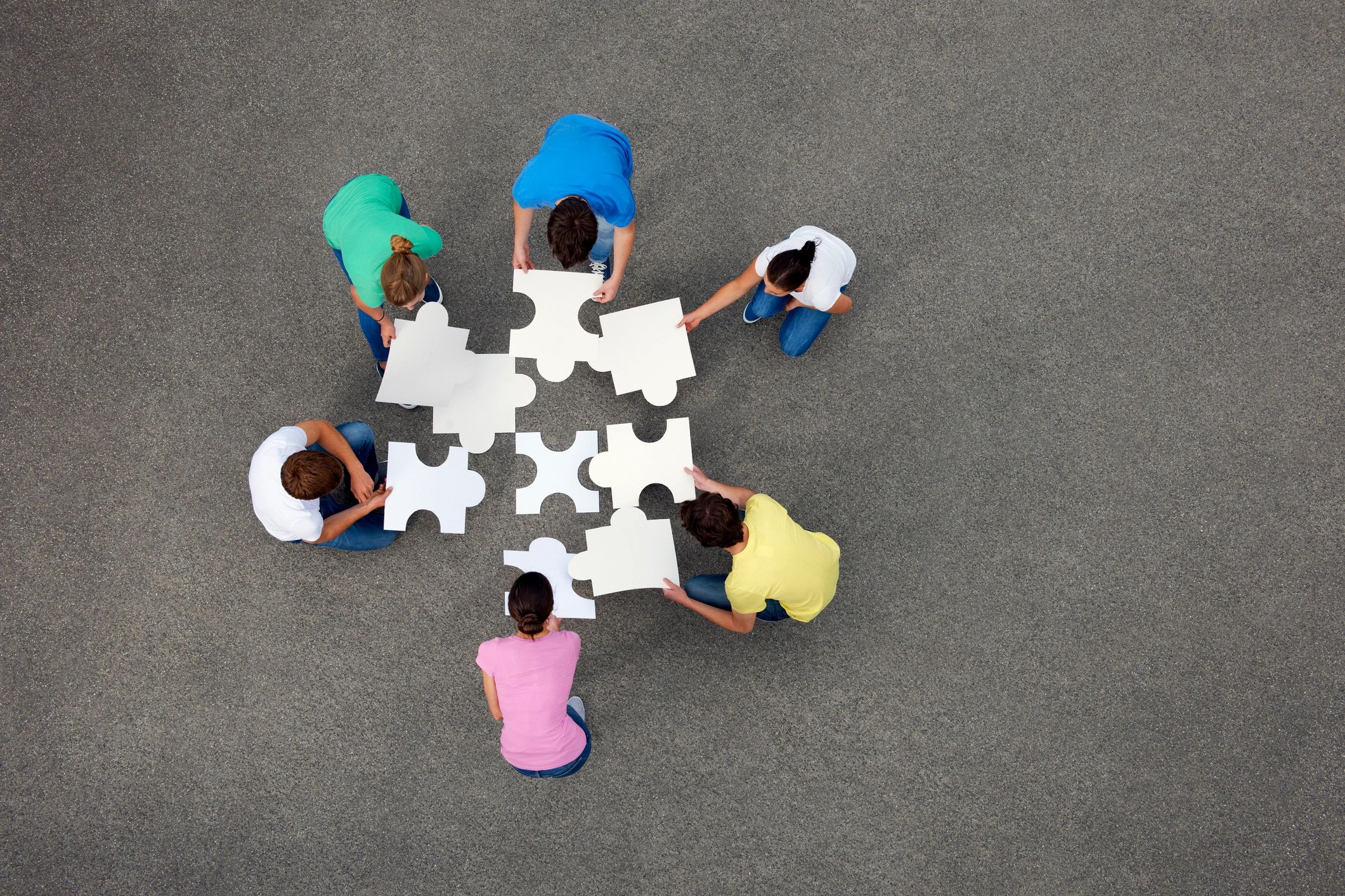 People collaborating around puzzle pieces representing our dedication